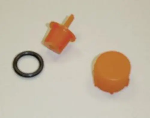 Drei orangefarbene Kunststoffteile, darunter ein Stopfen mit Abziehlasche und ein O-Ring, auf einem hellen Untergrund. Teile gehören zu einem Remeha Produkt.